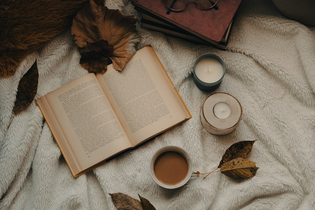 Offenes Buch mit warmem Getränk auf einer Decke